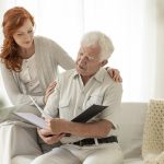 Senior man watching photo album during visit of granddaughter at